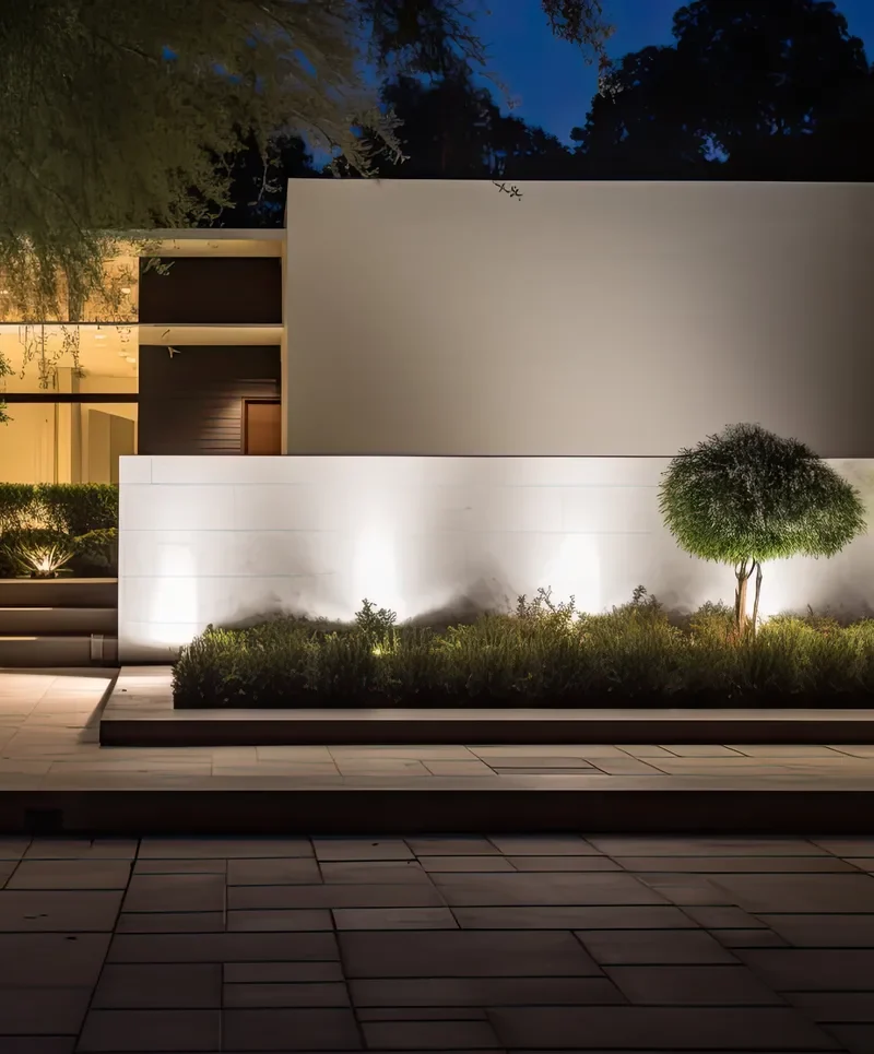 Landscape lighting illuminating the green shrubs next to the driveway.